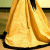 A static pixelated image of a golden bell with vertical striations and dark accents on its base, set against a blurred background.
