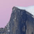 Pixelated mountain peak against a light purple sky with faint white cloud streaks, rendered in low-resolution digital style.