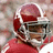 Pixelated image of a person wearing a red helmet and dark glasses with a red garment visible below.
