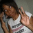 Pixelated image of a person in a white tank top making a hand gesture with fingers extended, set against a muted background.
