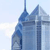 Pixelated blue and white image of a tall, modern building with a pointed spire against a light sky background.