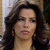 A pixelated close-up of a person with long dark hair, wearing red earrings and a dark top against a blurred background.