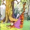 Tigger in a purple dress hugs a large yellow object in a forest setting with trees and green grass.