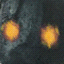 A dark, rocky figure with glowing orange eyes and a yellow-orange aura expands from a small shape into a full robot-like form against a textured background.
