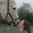 Pixelated static image shows a figure in dark clothing holding a light-colored object against a blurred background with green and gray tones.