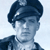 Static pixelated image of a person wearing a dark cap and jacket against a light background, with visible dithering and low-resolution rendering artifacts.