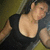 Pixelated image of a person in a black top with arms raised, set against a blurred background with green and brown tones.