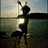 A pixelated image of a person dancing on a beach at sunset with text overlays in pink and gray