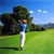 Pixelated static image of a golf player in mid-swing on a green field with trees and blue sky background.