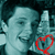 Pixelated image of a person with light skin tone wearing a white shirt, making a peace sign with their right hand, and a red heart symbol overlaid on the lower right.