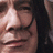 A pixelated image of a person's face with long dark hair on the left, and green pixelated text on a black background reading 'A fake only a mother could love' on the right.