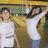 Two figures in white shirts pose with arms raised against a blurred background of yellow and green tones.