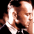 Pixelated static image of two male faces in close proximity with a black background, likely representing Bruce Willis and another person from the Die Hard franchise.
