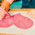 Pixelated image of a figure in pink pants and orange shoes standing on a light surface with teal and dark blue background elements.
