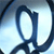A pixelated blue and white abstract shape resembling a stylized letter or symbol against a light blue gradient background.