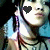 A person wearing a light blue shirt and multiple necklaces with heart-shaped pixel art over the eyes in black, pink, purple, red, and orange.