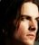 Pixelated close-up of a person's face with light skin tone, dark hair, and neutral expression against dark background.