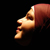 Pixelated profile of a human head with reddish-brown hair against a black background, showing facial features in warm tones.