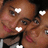 Pixelated close-up of two people with brown skin tones, one wearing a black top and white accents, surrounded by four white heart shapes.