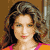Pixelated portrait of a person with wavy brown hair, light skin, and a neutral expression wearing a pink and orange top against a brown background.