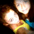 Two pixelated figures with light skin tones, one in a yellow top and blue accessory, the other in brown hair against dark background.