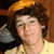 Pixelated image of a person with brown hair wearing an orange cap and yellow shirt, overlaid with black text boxes containing white text.