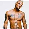 Static image of a shirtless man with tattoos and necklaces against a plain background.