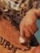 A hand presses a small white object against an orange surface with partial text, viewed from multiple angles in a