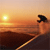Pixelated static image of a person standing on a beach at sunset with the sun low in the sky, rendered as a 50x50 buddy icon.