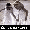 Two women in white dresses stand on a beach, holding hands and leaning toward each other as text changes across four