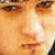 A pixelated close-up of a person's face with warm orange and brown tones, showing eyes, nose, and mouth in a static image.