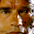 Pixelated close-up of a human face with warm brown and orange tones, showing eyes, nose, and part of the mouth against a light background.