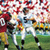 Pixelated static image of two figures in sports uniforms on a field with blurred background elements.