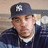 Pixelated image of a person wearing dark blue cap with white emblem, dark jacket over light shirt, and brown hair.