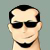 Pixelated static image of a person with short dark hair, wearing black sunglasses and a wide smile against a solid light gray background.