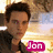 Pixelated image of a person with short dark hair wearing a black top, set against a blurred background with warm tones and a pink text box reading 'Jon'.