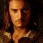 Two side-by-side pixelated images of a person with long brown hair, wearing a dark shirt with light collar details, against contrasting backgrounds.
