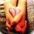 A person in orange shorts holds a pink heart-shaped object against a textured background.
