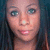 Pixelated close-up of a person's face with light skin, blue eyes, and dark hair against a dark background.