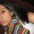 Pixelated close-up of a person with dark hair wearing a multicolored striped shirt, face turned left.