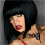 Pixelated image of a person with short black hair, red lips, and a red strap visible on their shoulder against a gray background.