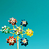 A static icon shows a yellow windmill with six flower-shaped blades in red, white, green, blue, and yellow against a solid teal background.