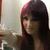 A pixelated image of a person with long dark hair and pink highlights, wearing a brown top against a light background.