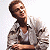 A pixelated image of a person in a light-colored jacket over a white shirt, standing against a bright background with green text reading 'Original Icons .com' on the right.