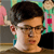 Pixelated close-up of a person with short dark hair, light skin, and glasses, wearing a white shirt against a blurred background with green and pink elements.