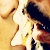 Pixelated static image of two figures in a close embrace with one figure holding the other's face, set against a warm-toned background.