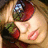 Pixelated close-up of a person's face with closed eyes, red lips, and a red and green headpiece under warm lighting.