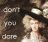 Pixelated static image with text 'don't you dare' in light gray on dark brown background, featuring a partially visible figure with light skin and dark hair.