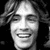 Black-and-white pixelated static image of a smiling person with long hair, displayed as a 50x50 buddy icon on a dark background.