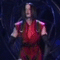 A person in a red outfit with dark sleeves performs sequential hand movements against a dark circular-patterned background.
